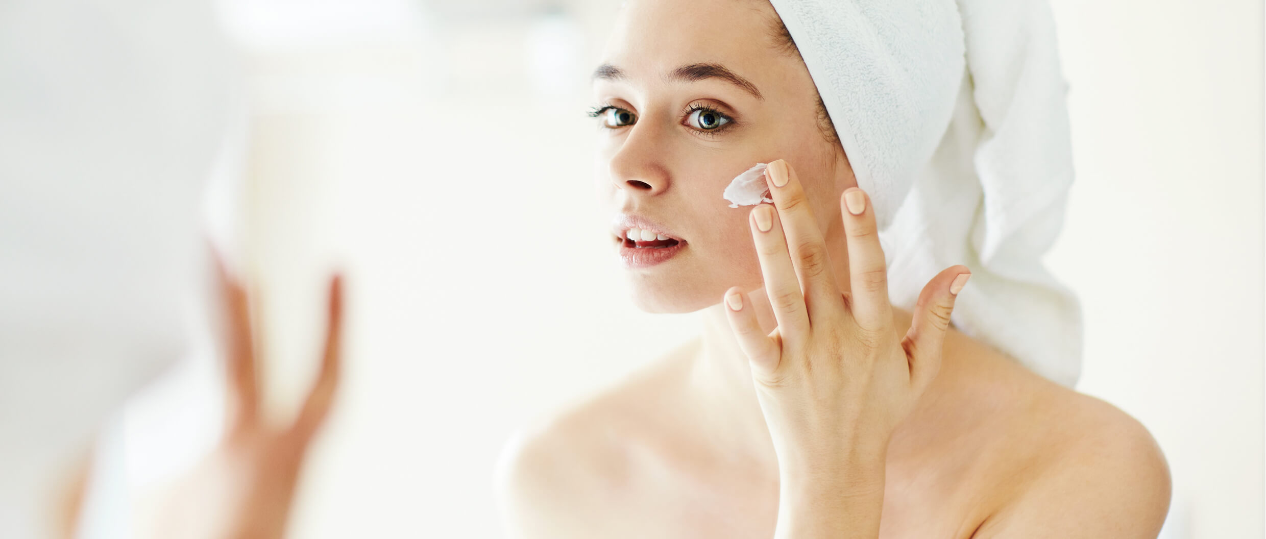 A woman applying a skincare product on her face
