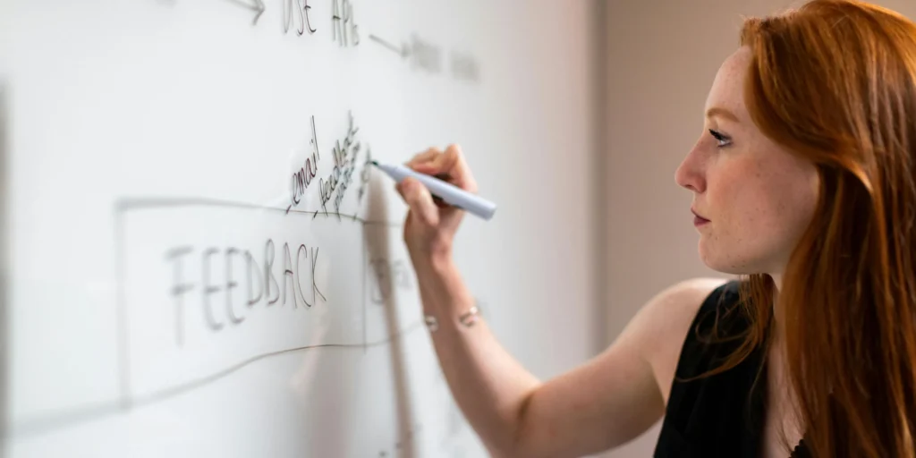 Woman writing on the board with black marker