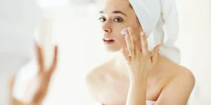 Girl applying cream on the face after shower