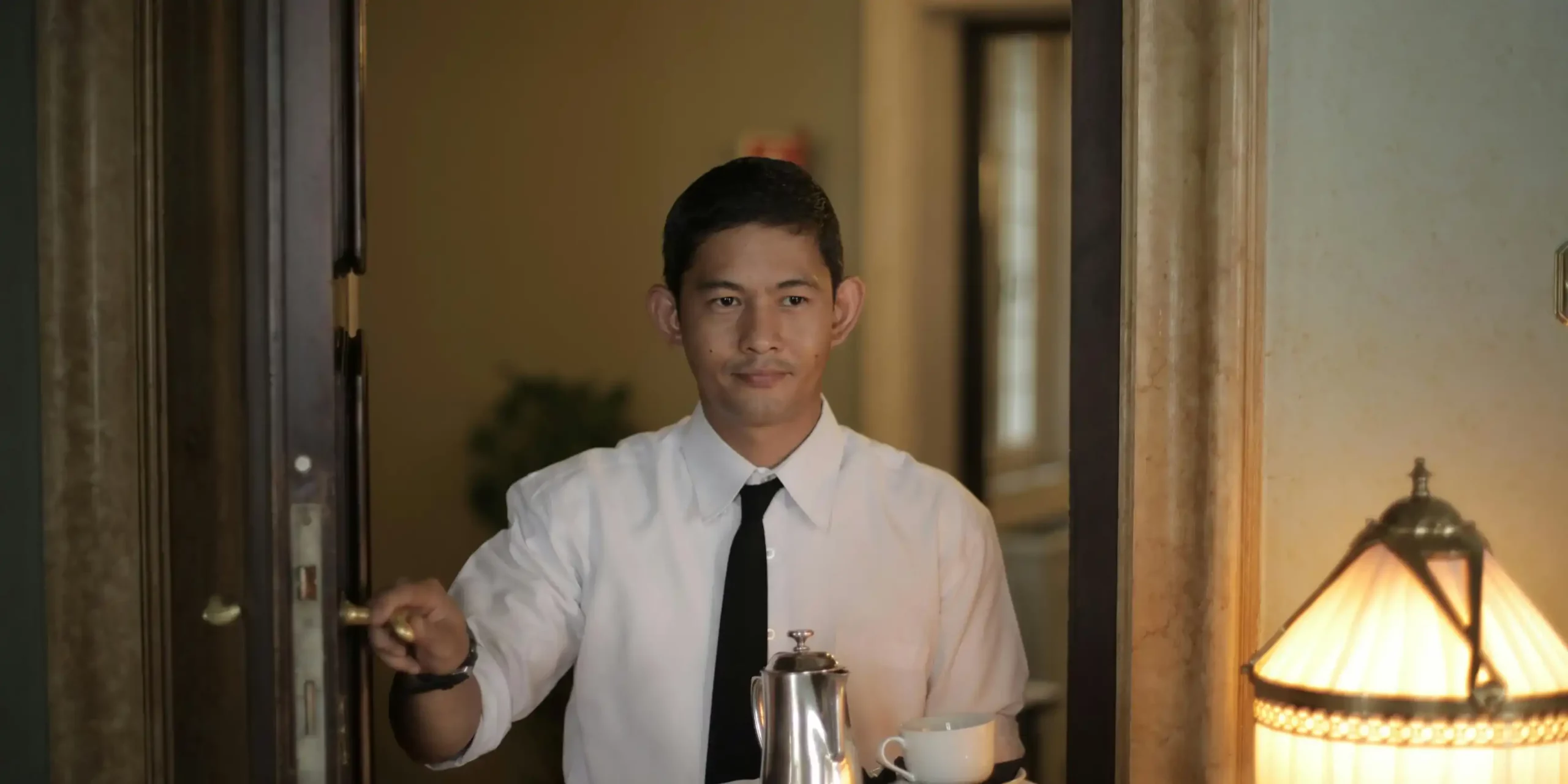 Hospitality employee opening a door with a teaset on a tray