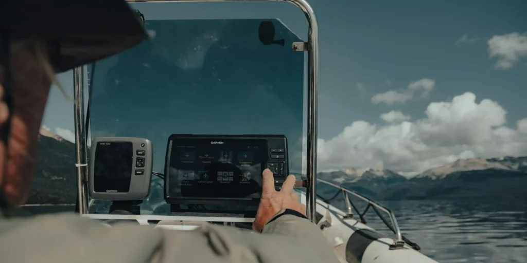 man touching navigation tool in small boat on a lake