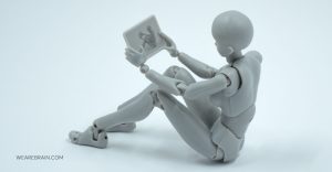 A figurine looking at a tablet