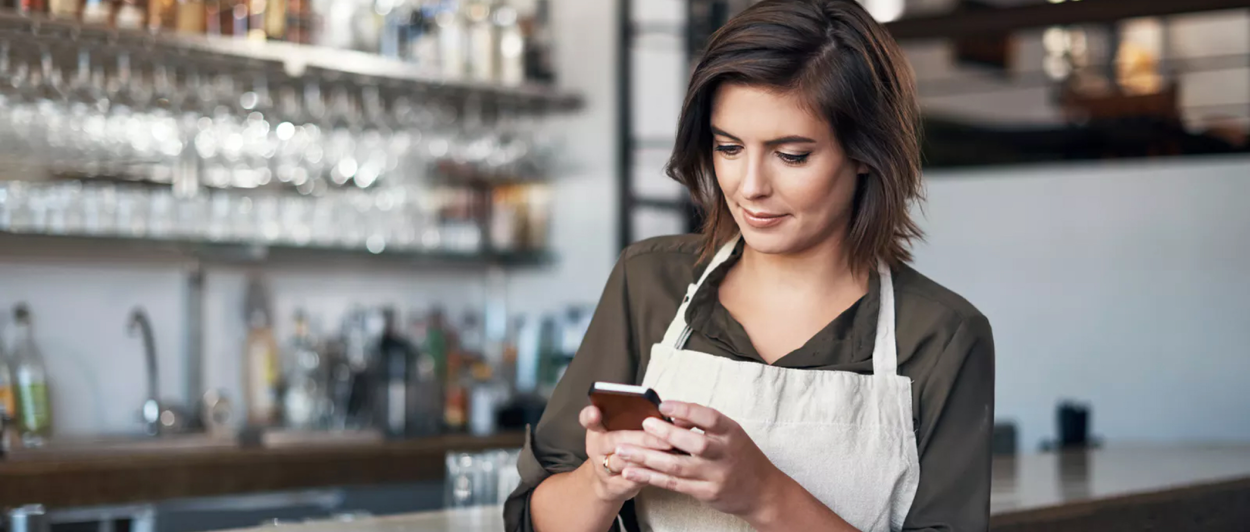 A bartender checking her phone