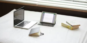 Photo of a laptop and ipad with books and a notebook