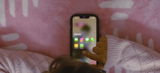 Kid's hand choosing social media on iphone's screen