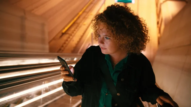 A woman on the escalator looking on her phone