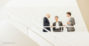 3 men in conversation in the white room on white stairs