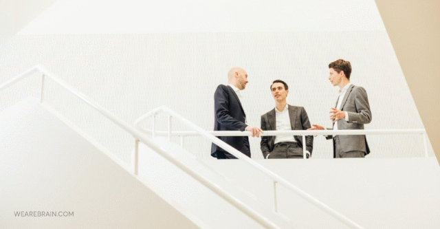 3 men in conversation in the white room on white stairs